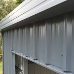 colorsteel-cladding-detail-nz Close-up of Colorsteel cladding and flashing detail on a steel shed showing clean lines and weatherproof finish