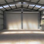 finished-kitset-shed-interior-nz Interior of completed steel shed showing open span, roller doors, and clean structural layout