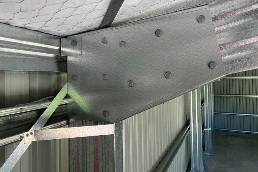 Steel shed knee connection with heavy bolted plate joining column and rafter