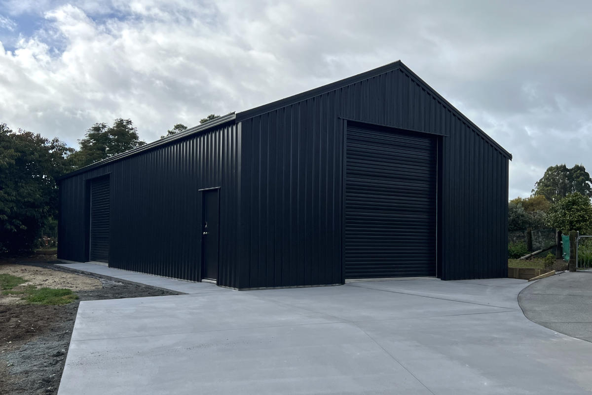 Large black steel building with roller doors