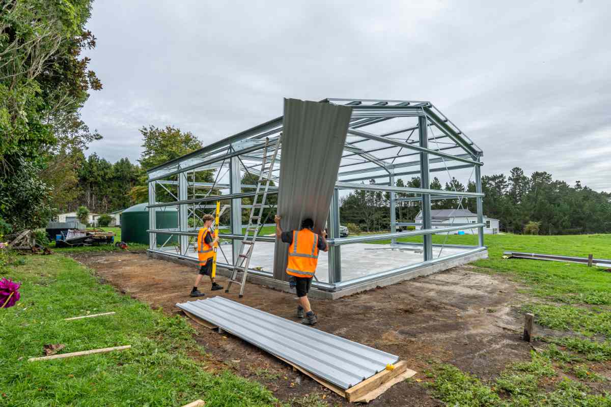 Builders installing cladding on a shed frame